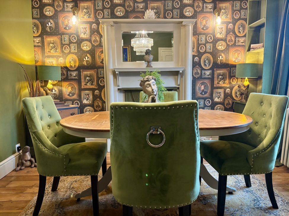 A dining room with a round table and green chairs at Liberty House in Ashbourne