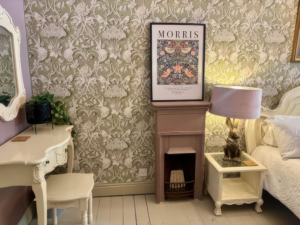 A bedroom with a mirror, plant, side table, and lamp at Liberty House Ashbourne