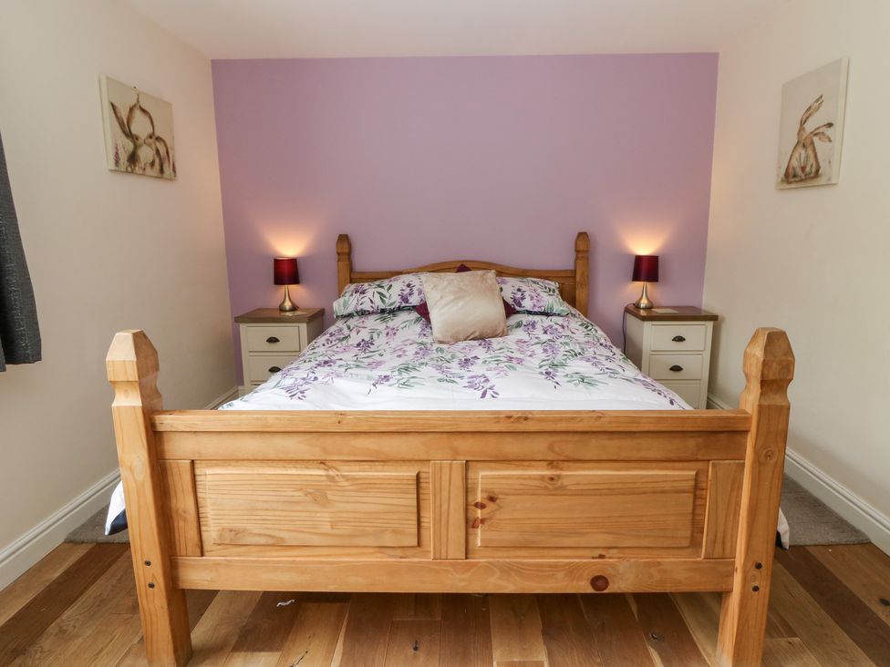 A bedroom featuring a wooden bed with floral bedding at New Peny in Llandrindod Wells