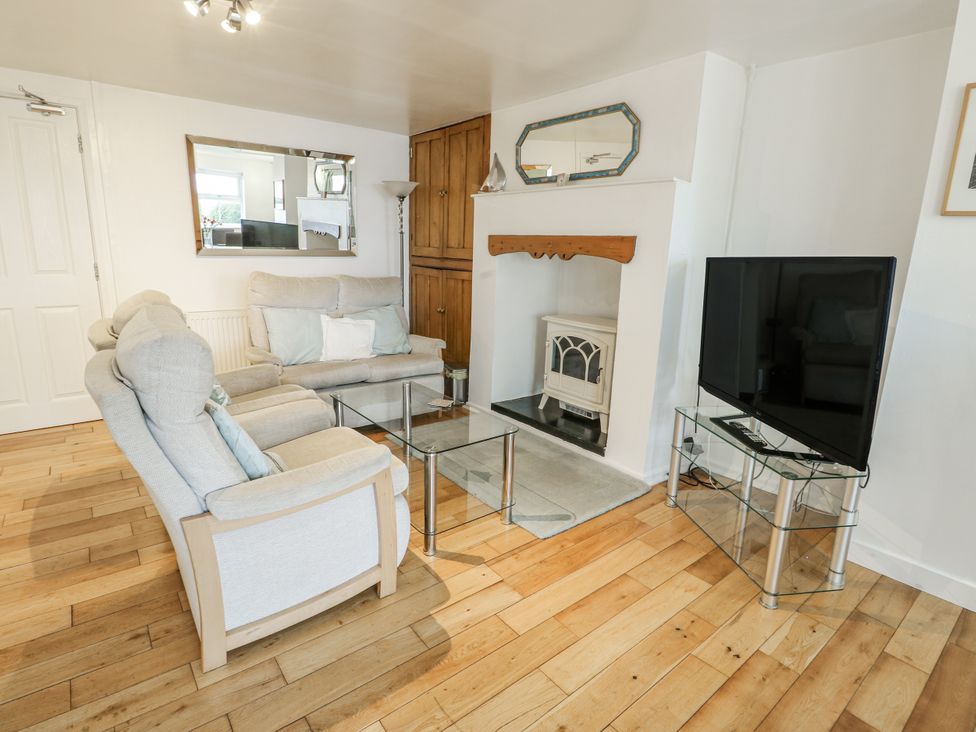 A living room with a sofa, coffee table, and television at Preswylfa Apartment in Caernarfon