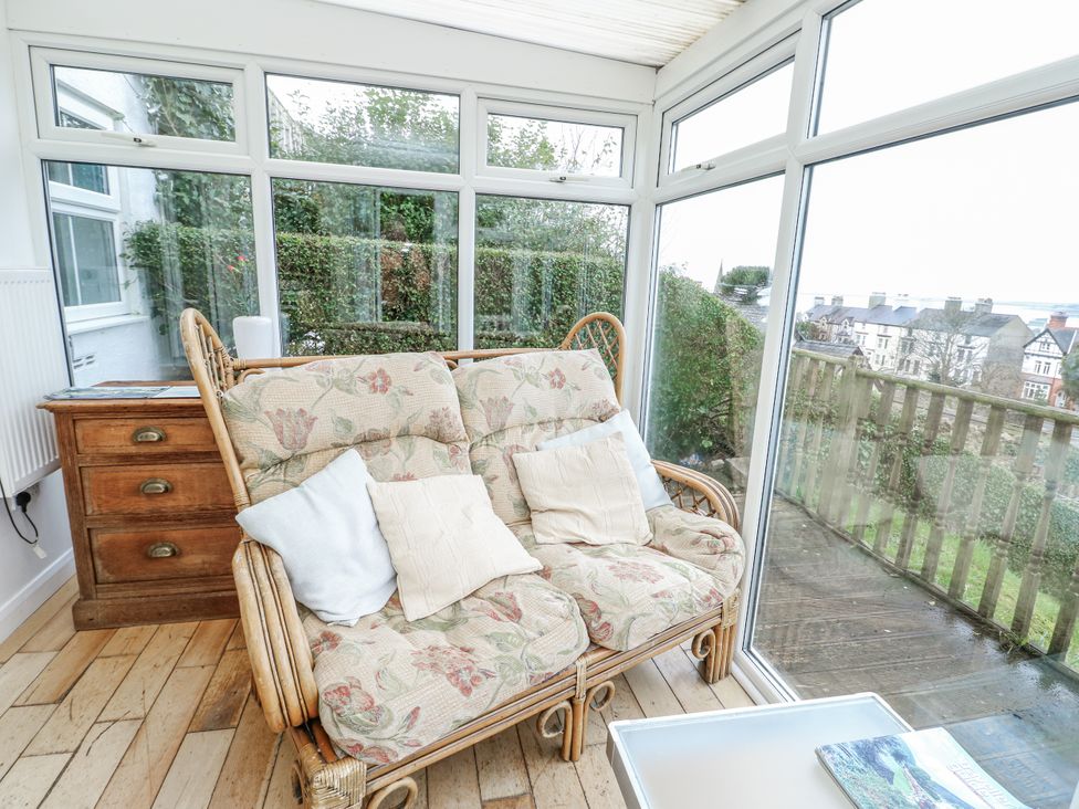 A conservatory with a sofa and a side table at Preswylfa Apartment in Caernarfon