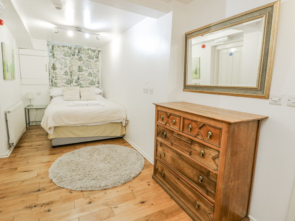 A bedroom with a bed, dresser, and mirror at Preswylfa Apartment in Caernarfon