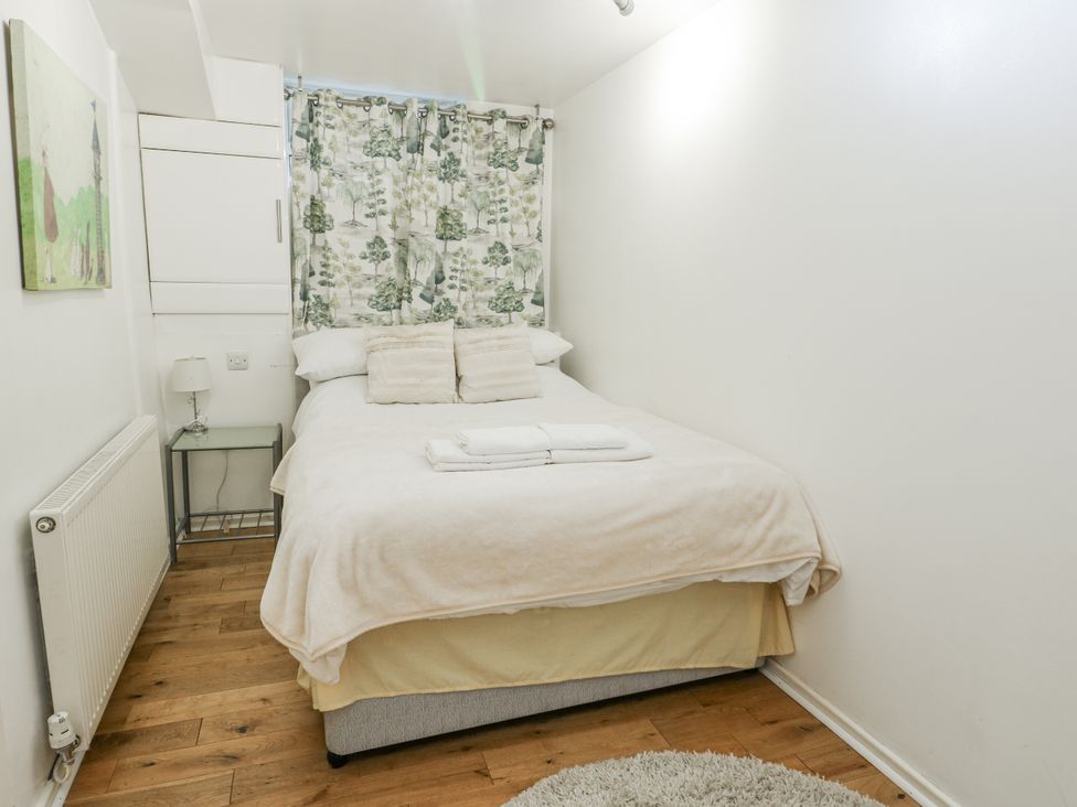 A bedroom with a bed and a bedside table at Preswylfa Apartment in Caernarfon