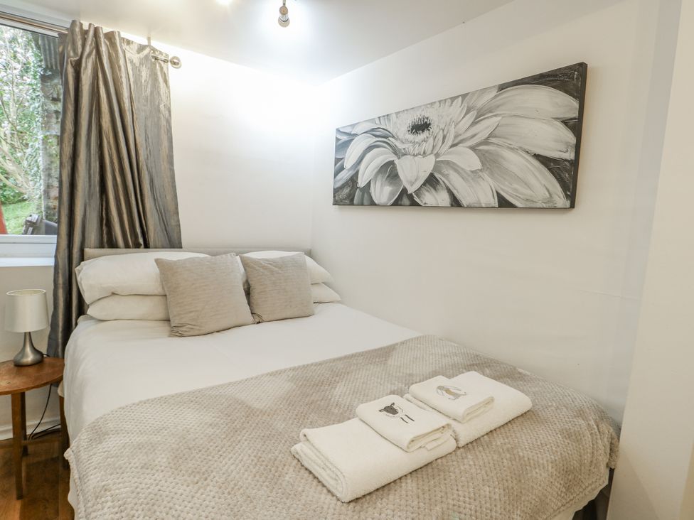 A bedroom with a bed and side table at Preswylfa Apartment, Caernarfon
