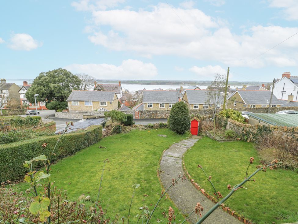 A garden with a pathway and houses in the background at Preswylfa Apartment in Caernarfon