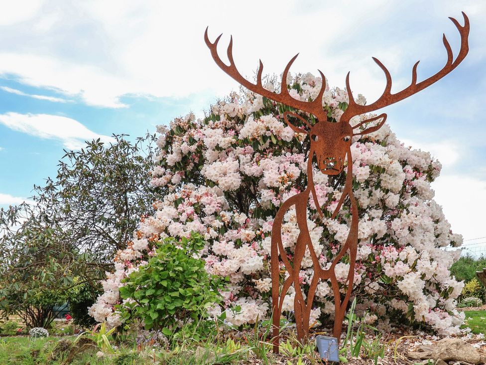 A metal deer sculpture in front of a flowering bush at Erin Cottage Pelynt near Looe