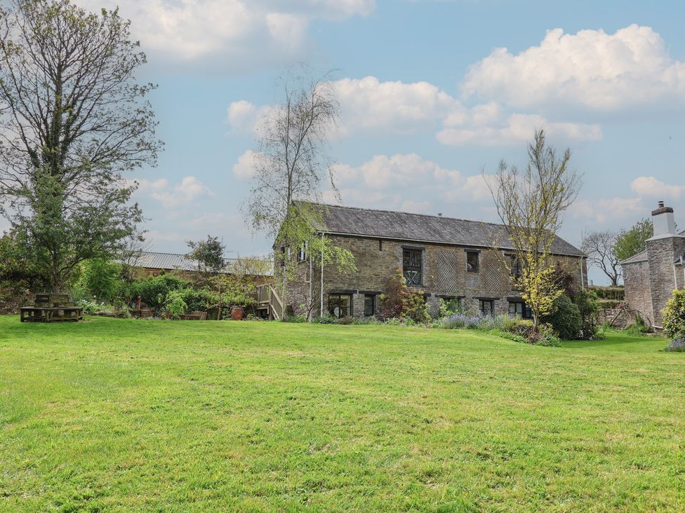 A building with surrounding grass and trees at Erin Cottage in Pelynt near Looe