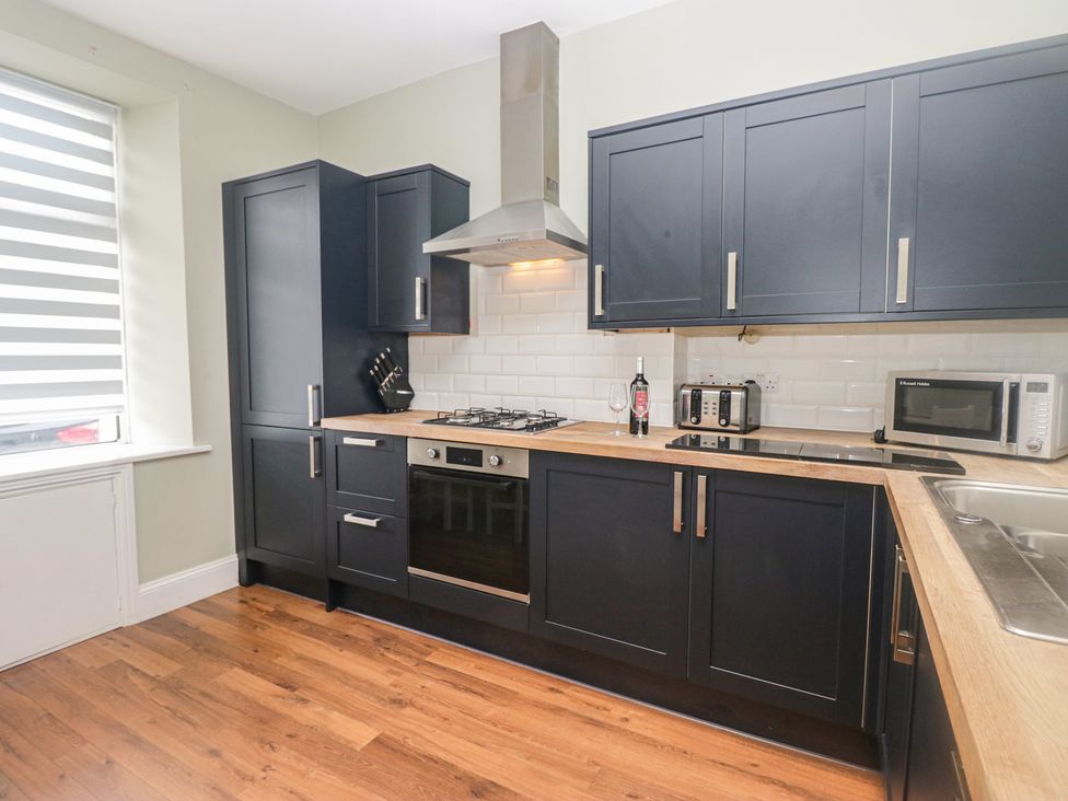 A kitchen with cabinets and appliances at Molly's Cottage in Flookburgh