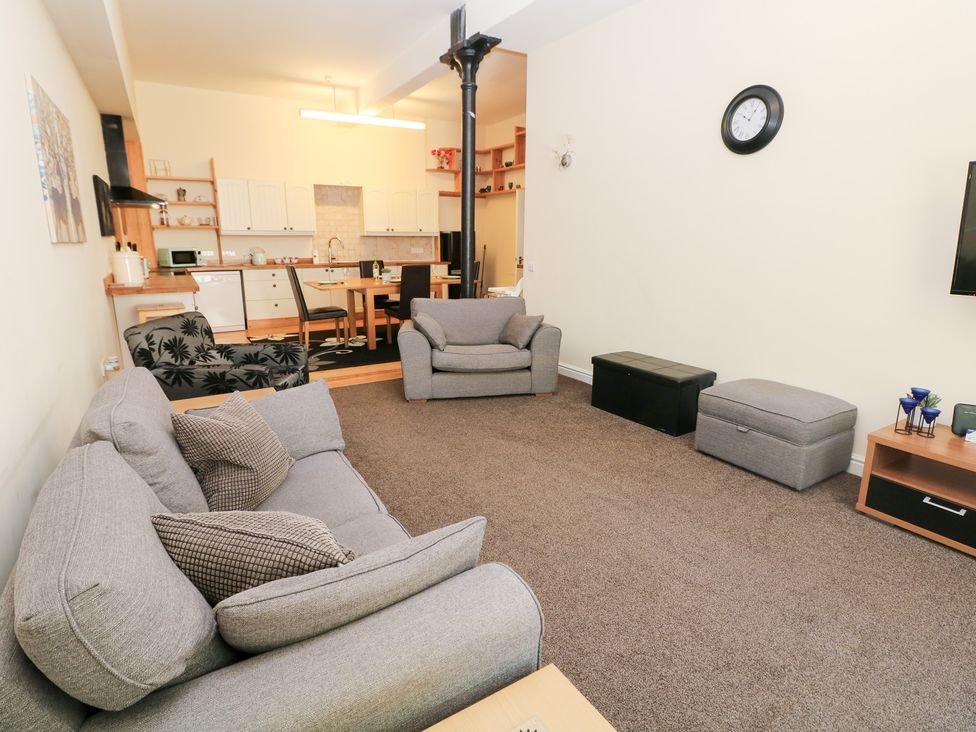 A living room with furniture including a tv and dining area at Wye Apartment, Litton Mill in Miller's Dale