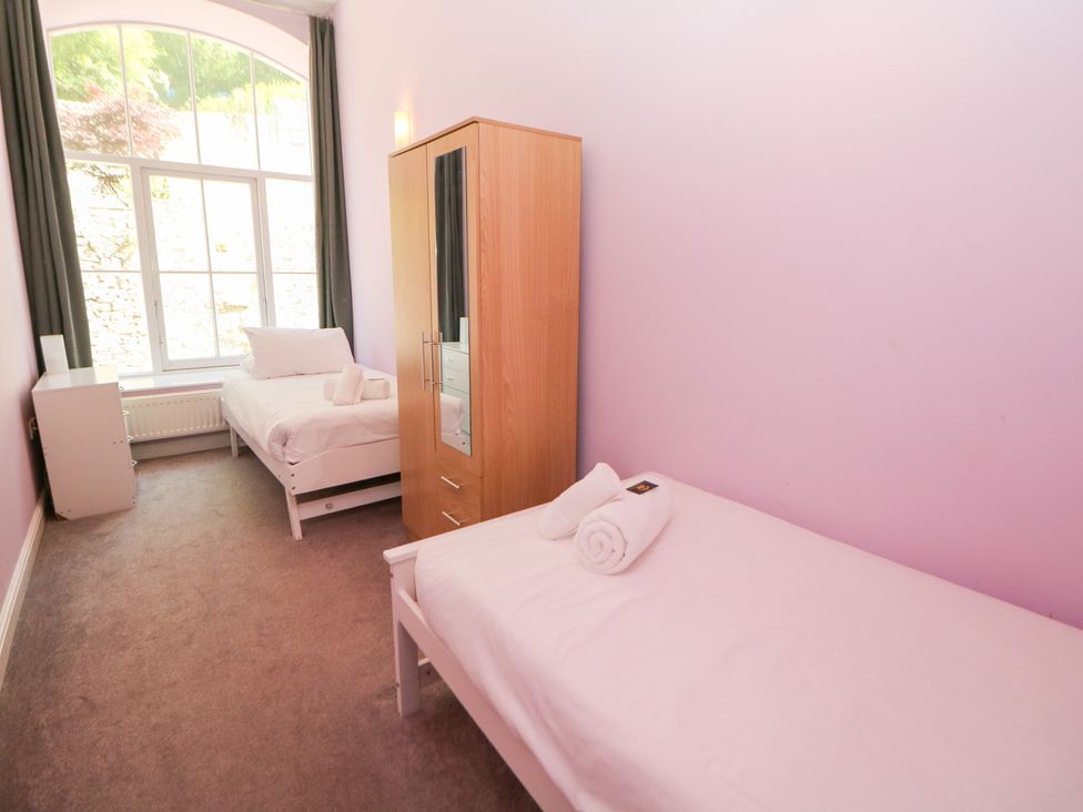 A bedroom with two beds and a wardrobe at Wye Apartment, Litton Mill in Miller's Dale