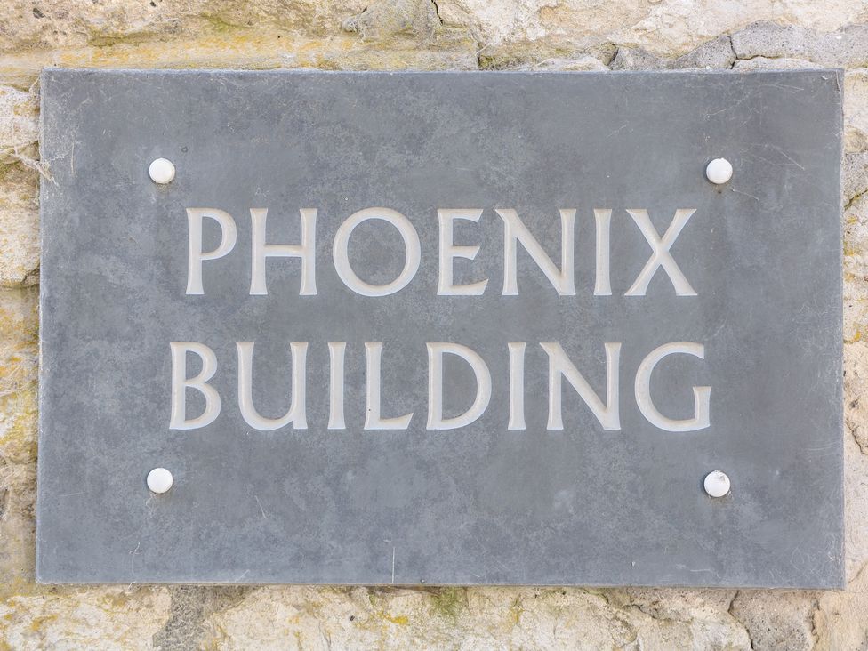 A sign displaying the name Phoenix Building on a stone wall at Wye Apartment, Litton Mill