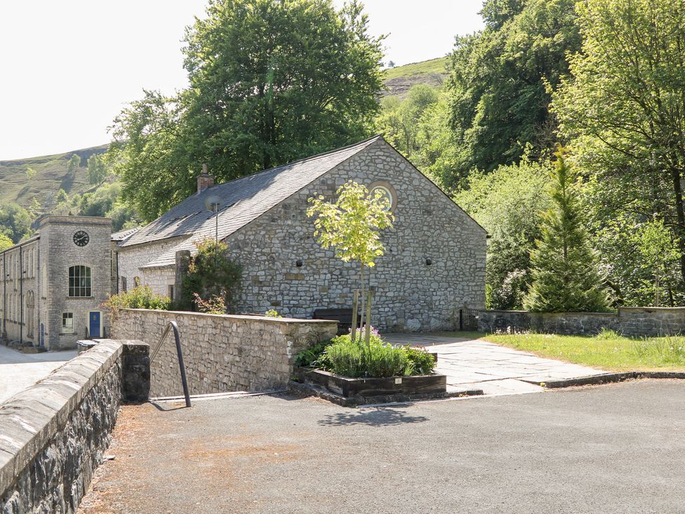 A stone building with a clock and trees at Wye Apartment, Litton Mill