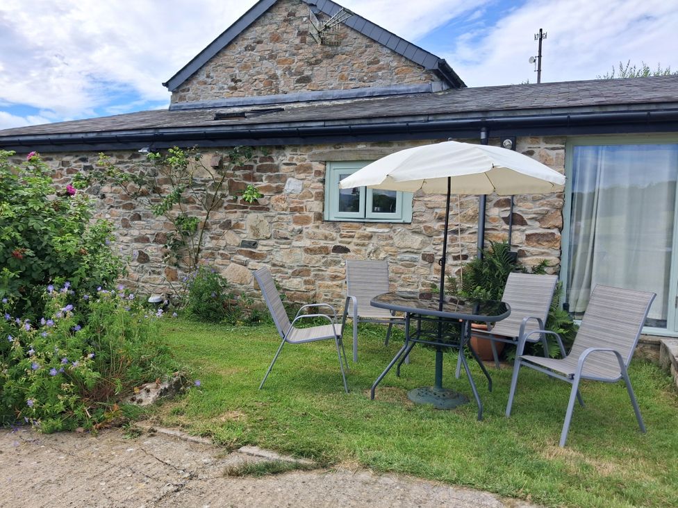 A garden with a table and chairs at Owl Barn in Tavistock