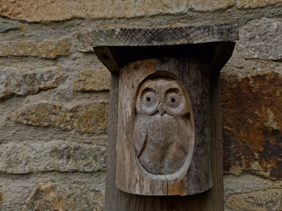 A wooden owl carving mounted on a stone wall at Owl Barn Tavistock