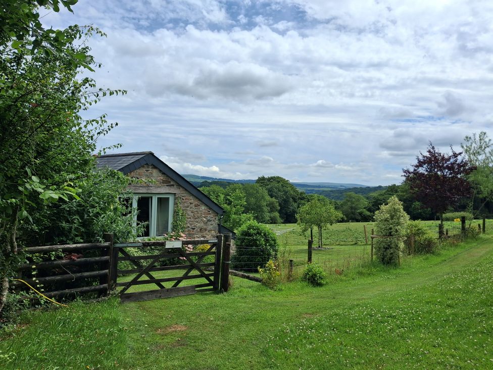 A stone house with a gate and fence in a field at Owl Barn Tavistock