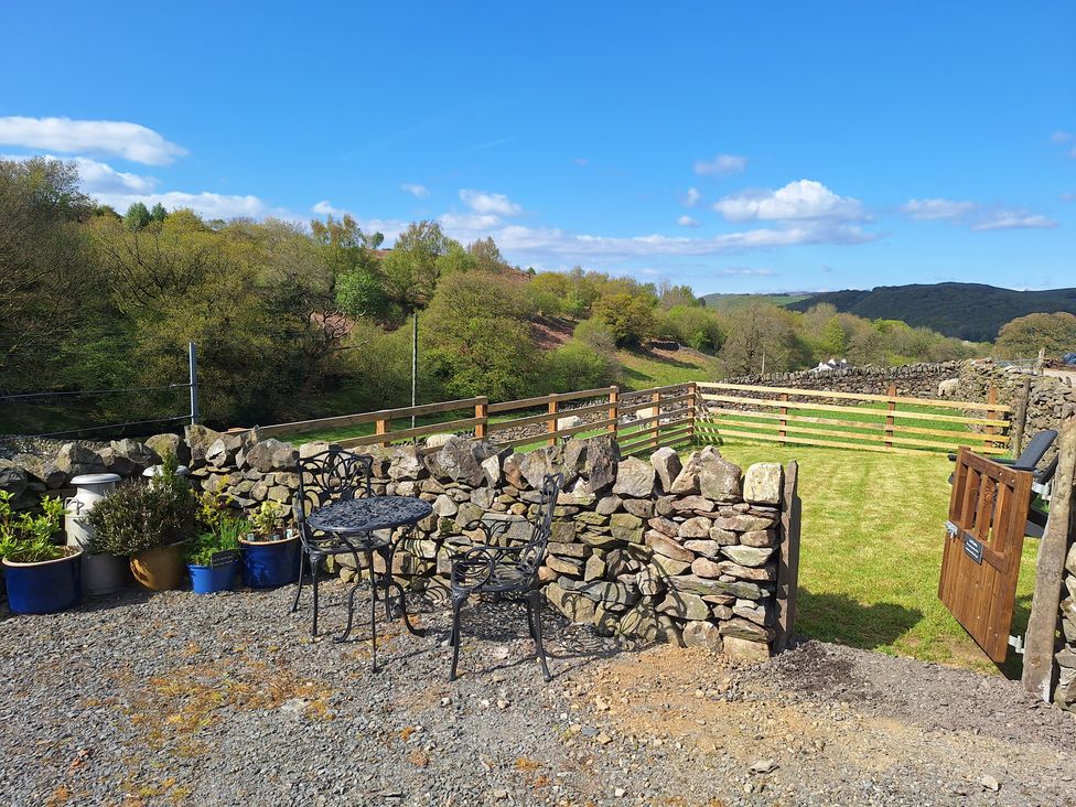 A garden with a table and chairs surrounded by a stone wall at La'al Riddings, Lowick Green, Riddings Farm Near Ulverston